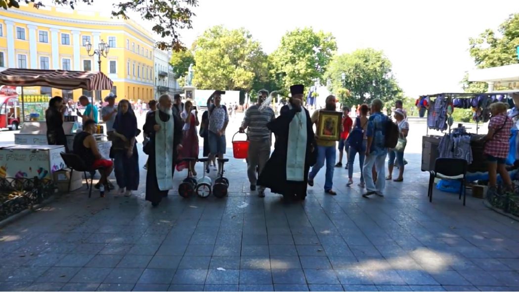 Un prêtre orthodoxe répand de l’eau bénite après une Gay Pride